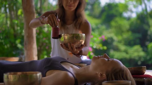 Superslowmotion Shot of a Woman Master of Asian Sacred Medicine Performs Tibetan Bowls Healing