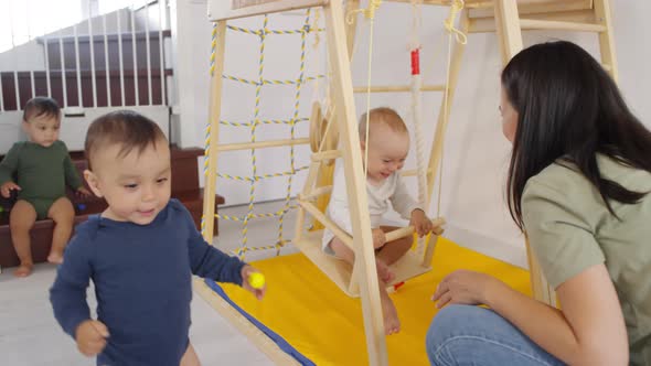 Asian Mom Entertaining Kids on Indoor Playground alt