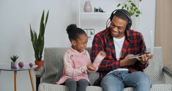 Father Black Operator Man Wears Headphones on Head Holds Laptop Plays Game with Beloved Daughter on