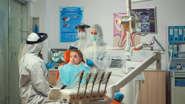 Pediatric Dentist Wearing Protection Suit Treating Girl Patient