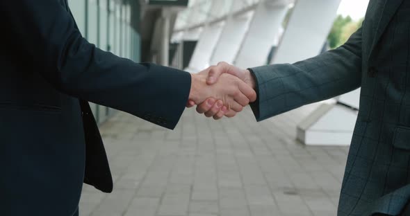 Close Up Hands of Top Managers Shaking Hands with Each Other Standing Outdoors Near Office Building