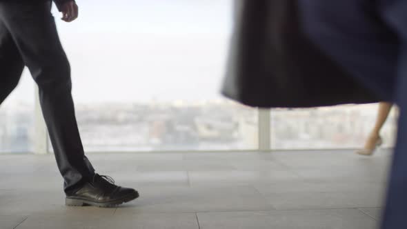 Unrecognizable Businesspeople Walking before Panoramic Window