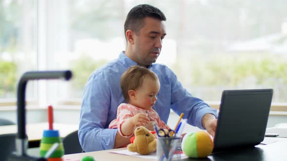 Father with Baby Working on Laptop at Home Office