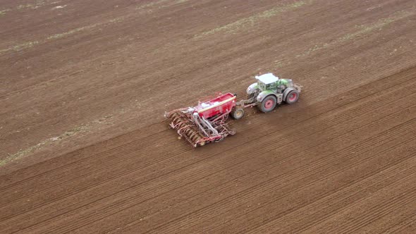 Tractor in Working in the Field. Tractor with a Modern Sowing Seeds Machine in a Newly Plowed Field