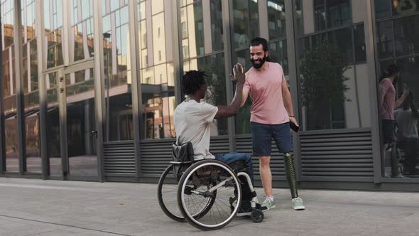 Multiethnic friends with physical disabilities walking together by the city - Diversity lifestyle