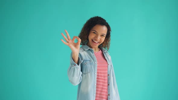 Portrait of Good-looking African American Lady Showing OK Gesture and Laughing