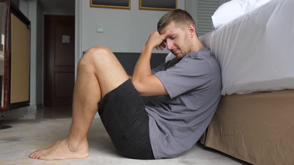 The Lonely Sad and Hopeless White Man Sitting on the Floor Holding His Head