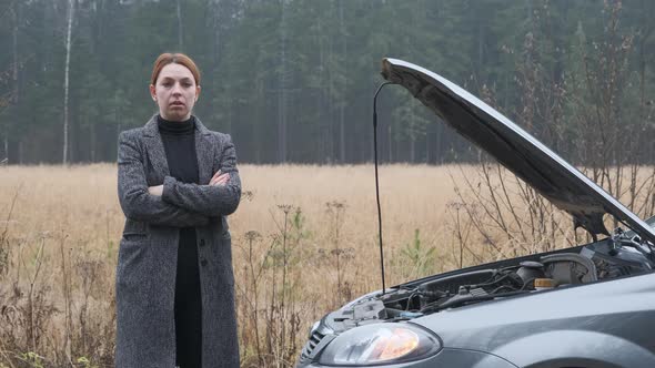 Stressed Female Driver Standing By Broken Car