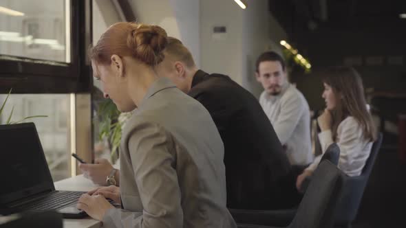 Portrait of Intelligent Businesspeople at Open Space Office. Side View of Caucasian Office Workers