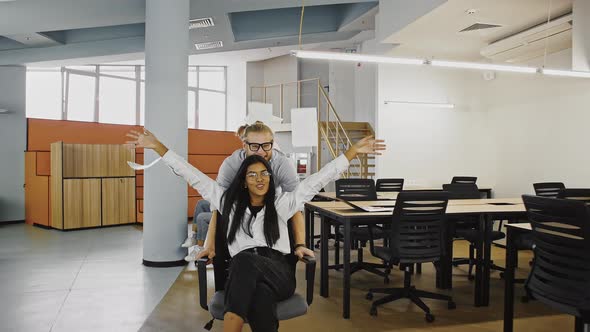 Young Multiethnic Diverse Employees are Throwing Up Documents or Papers While Riding Chairs in