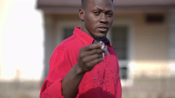 Wealthy Successful African American Young Man Showing Keys From New House Looking at Camera Standing