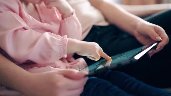 CU, : Young Cute Mother and Little Girl Are Sitting on the Couch and Teaching Using a Tablet