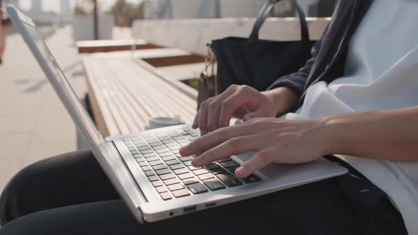 Hands Typing on Laptop Outdoors