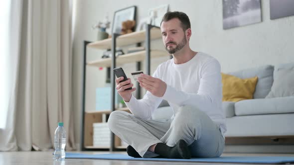 Man Making Online Payment on Smartphone on Yoga Mat