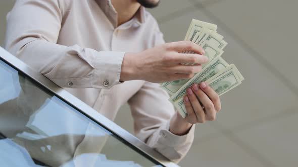 Closeup of Male Hands Counting Dollar Bills Outdoors