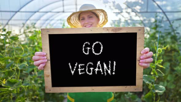 Smiling woman with a sign in her hands calls for healthy food. Vegetarianism, vegan