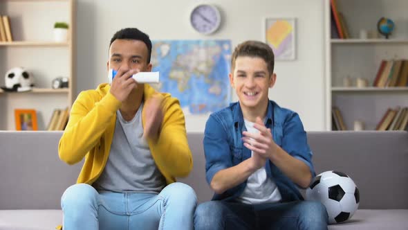 Teenage Soccer Fans Cheering for National Football Team at Home Blowing Vuvuzela