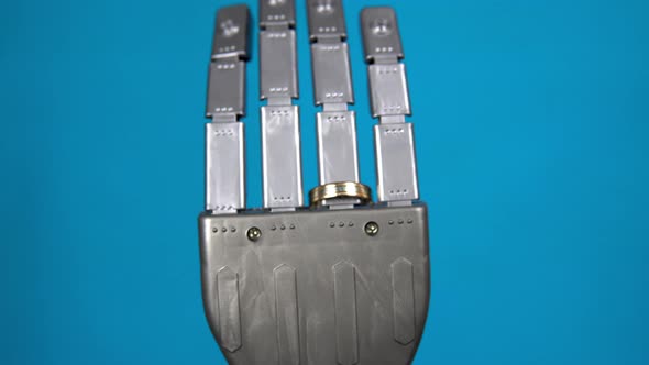 A Mechanical Hand with a Ring on the Ring Finger. Gray Cyborg Hand on a Blue Background. The Camera