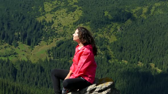 The girl sits on the top of the mountain and meditates. Relax in nature. Happiness and tranquility