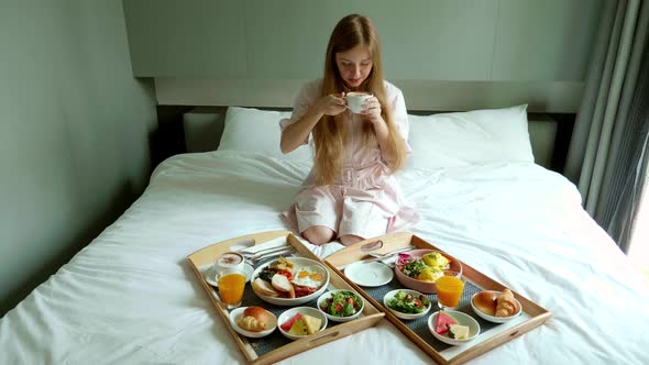 Breakfast in Bed Happy Woman Sitting on Bed in Hotel Drinking Coffee