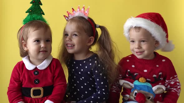 Emotion Cute Happy Cheerful 3 Siblings Friends Baby Girl Boy Hug in Santa Suit Looking On Camera At