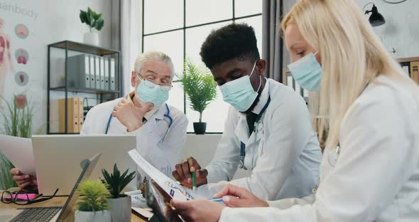 Male and Female Doctors in Masks Discussing Medical Moments in Their Job During consultation