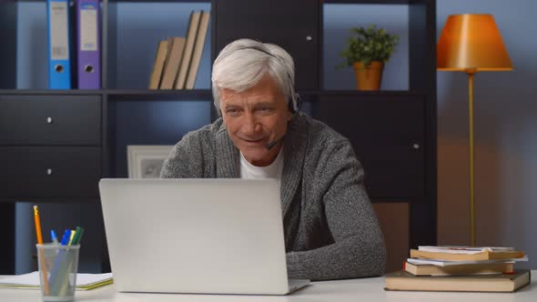 Retired Man in Headset Working As Freelancer in Internet From Home Office.