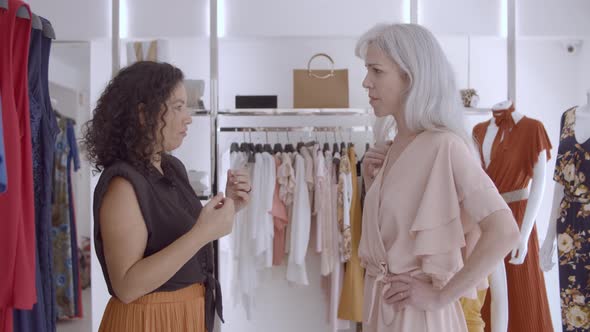 Friendly Shop Assistant Helping Female Customer in Fitting Room