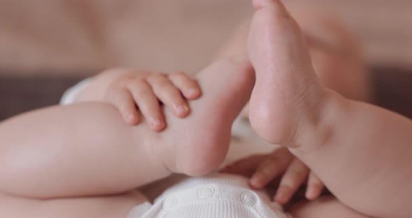 Close Up Feet of a Beautiful Sleeping Baby Naked in Diapers with Pacifier in Bed Baby Grabs Its Feet