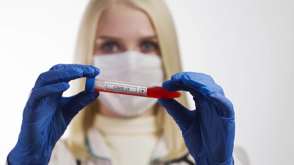 Female Doctor in a Protective Suit and Gloves Holds a Blood Test Tube To Check a Blood Sample for