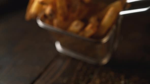 French fries falling on wooden table. Slow Motion. alt