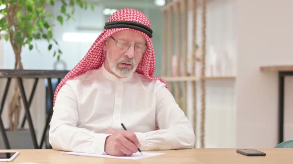 Senior Old Arab Businessman Writing on Paper