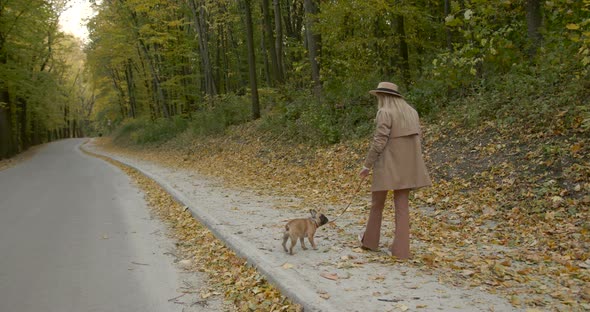 Rear View of Woman Walking with Dog in Autumn Park