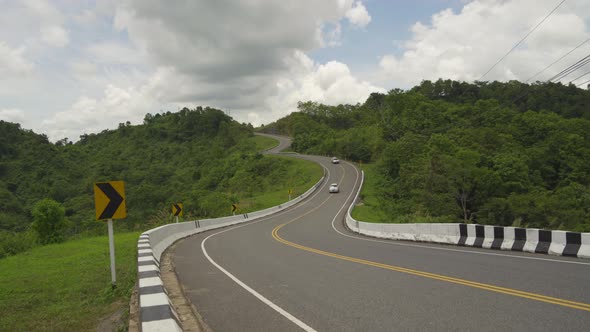 Cars driving on zigzag curve road or street on mountain hill with green natural forest