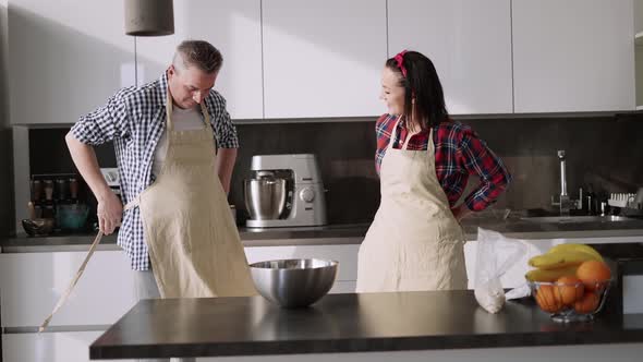 Romantic Couple at Home in the Kitchen Putting Aprons