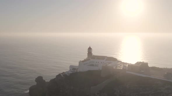 Cinematic aerial tracking shot of cape Saint Vincent lighthouse with sun setting