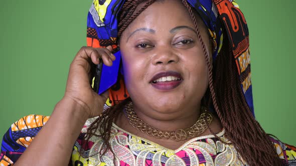 Overweight Beautiful African Woman Wearing Traditional Clothing Against Green Background