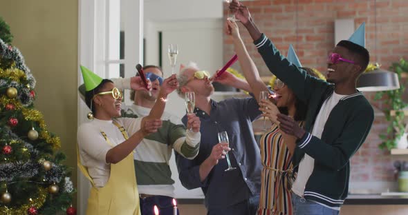 Happy group of diverse friends in party hats celebrating together, toasting with vine