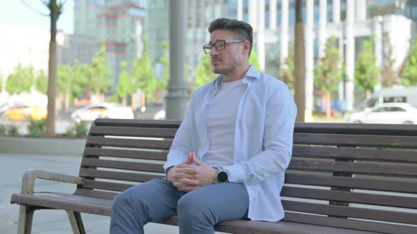 Waiting Man Checking Time While Sitting Outdoor on Bench