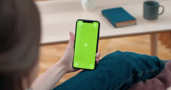 Backside View of Deaf Person Holding and Looking at Smartphone Green Screen. Woman Using Sign