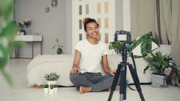 Good-looking African American Girl Creative Blogger Is Recording Video About Plants Sitting on Floor