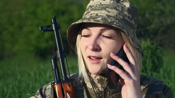 Ukrainian Woman Soldier with an Assault Rifle Calling Someone on the Phone