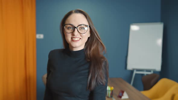 Confident and Smiling Business Woman in Glasses of Caucasian Appearance Standing in the Office and