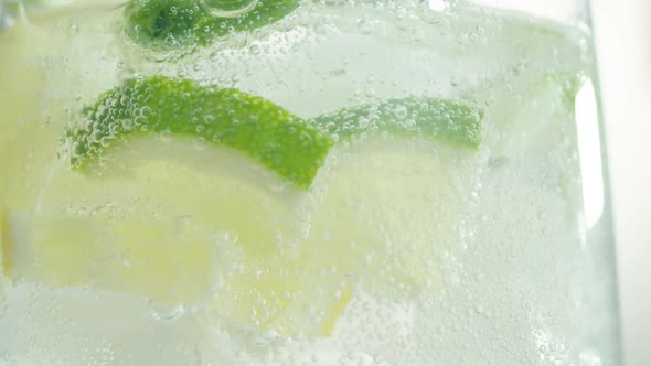 Bubbles Rise Up Inside Glass of Sparkling Water with Lime