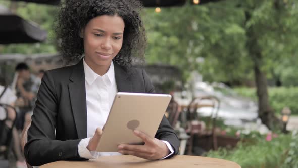Online Video Chat on Tablet By African Woman Sitting in Outdoor Cafe