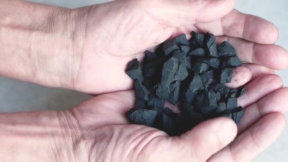 Close-up of black coal in the hands of a worker. Work in the mine theme.