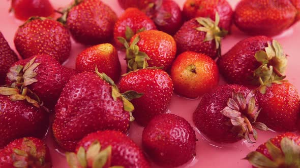 Splashes of water fall on strawberries. Slow motion.