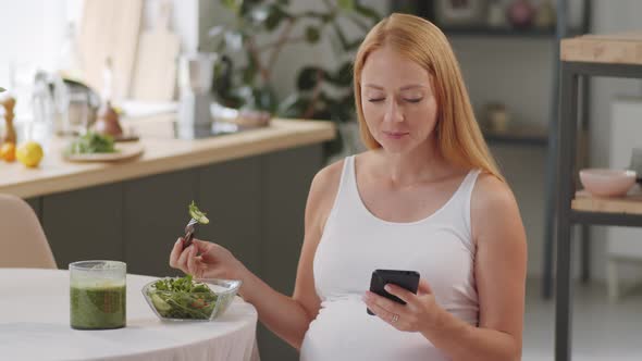 Pregnant Woman Eating Salad and Using Smartphone