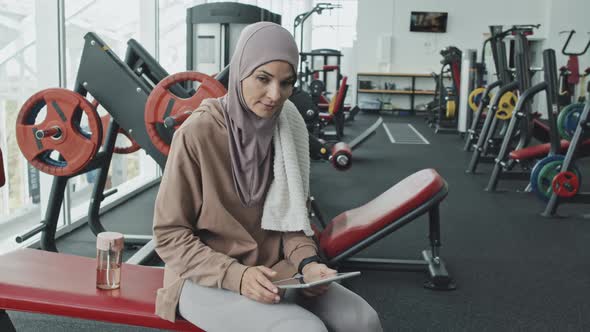 Portrait of Happy Woman in Hijab with Tablet at Gym