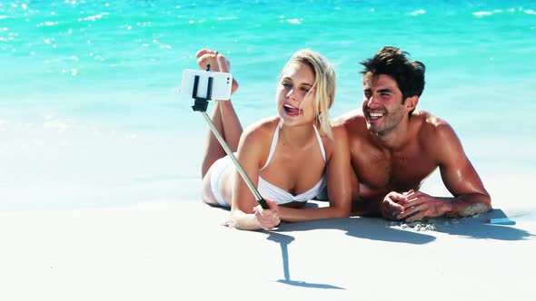 Couple lying on beach and taking a selfi from mobile phone